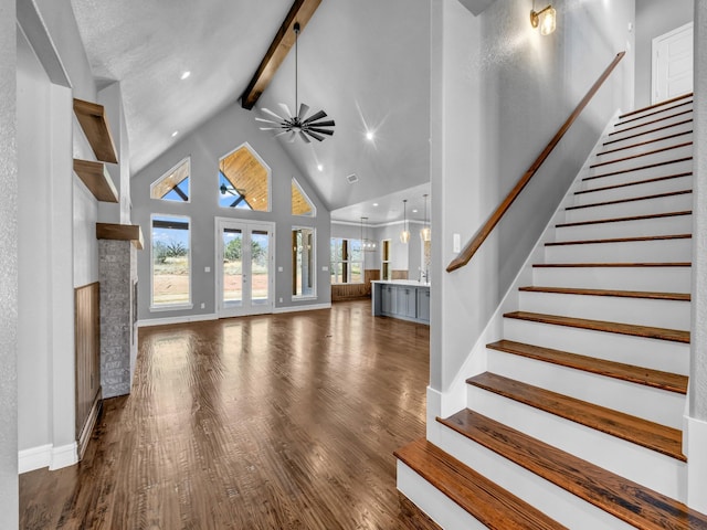 unfurnished living room with beamed ceiling, stairway, dark wood-style flooring, and high vaulted ceiling