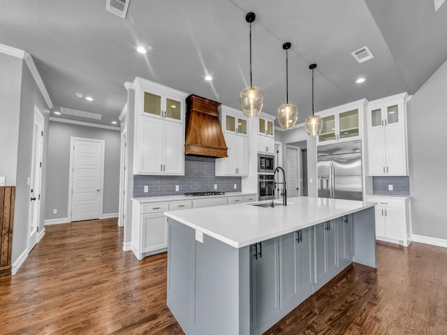 kitchen with visible vents, a spacious island, built in appliances, custom exhaust hood, and a sink