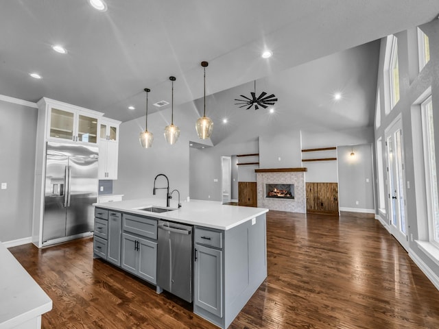 kitchen featuring gray cabinetry, stainless steel appliances, a sink, light countertops, and dark wood-style floors