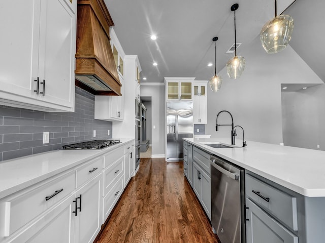 kitchen with appliances with stainless steel finishes, light countertops, gray cabinetry, premium range hood, and a sink