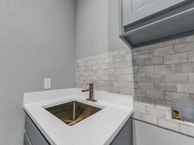 kitchen with gray cabinets, a sink, and a textured wall