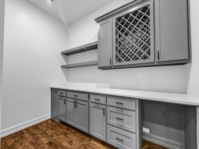 interior space with dark wood-style flooring, a dry bar, and baseboards