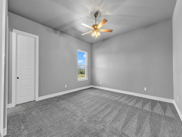 empty room with ceiling fan, dark colored carpet, and baseboards