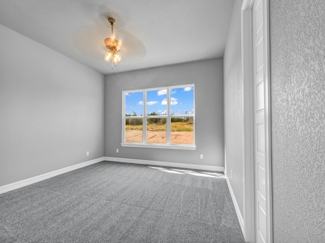 carpeted empty room featuring ceiling fan and baseboards