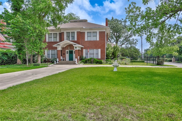 view of front of home featuring brick siding, a front yard, and fence