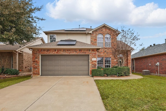 traditional home with driveway, roof mounted solar panels, a front yard, an attached garage, and brick siding