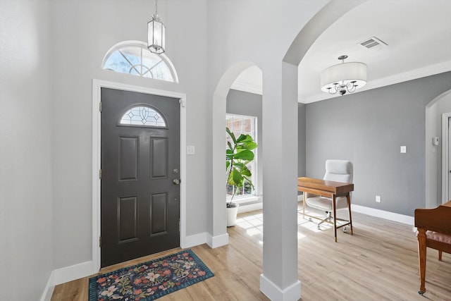 foyer with arched walkways, visible vents, a healthy amount of sunlight, and light wood-type flooring