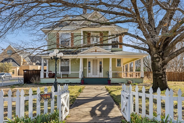 view of front of house with covered porch, a fenced front yard, and a balcony