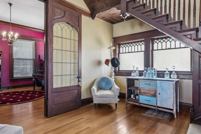 sitting room with stairs, hardwood / wood-style floors, baseboards, and a notable chandelier