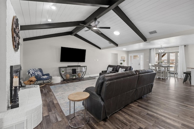 living room featuring vaulted ceiling with beams, ceiling fan with notable chandelier, a fireplace, visible vents, and dark wood finished floors