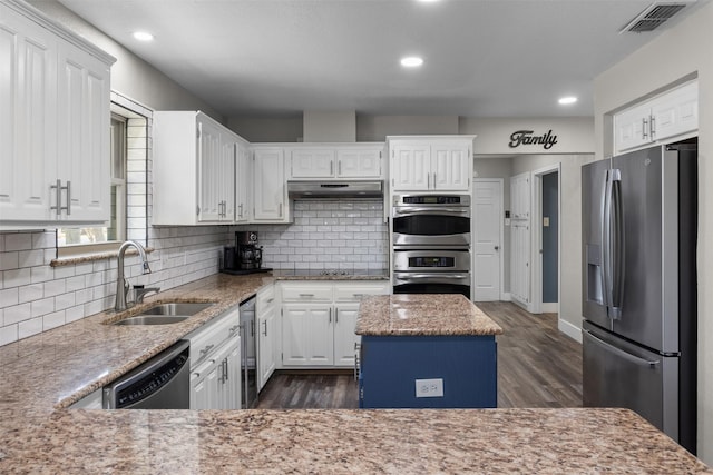 kitchen featuring under cabinet range hood, a sink, visible vents, appliances with stainless steel finishes, and a center island