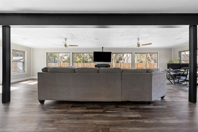 living room with ceiling fan, baseboards, dark wood-type flooring, and a wealth of natural light