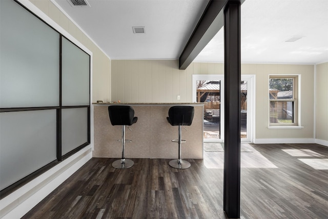 interior space with dark wood-style floors, beamed ceiling, visible vents, and baseboards