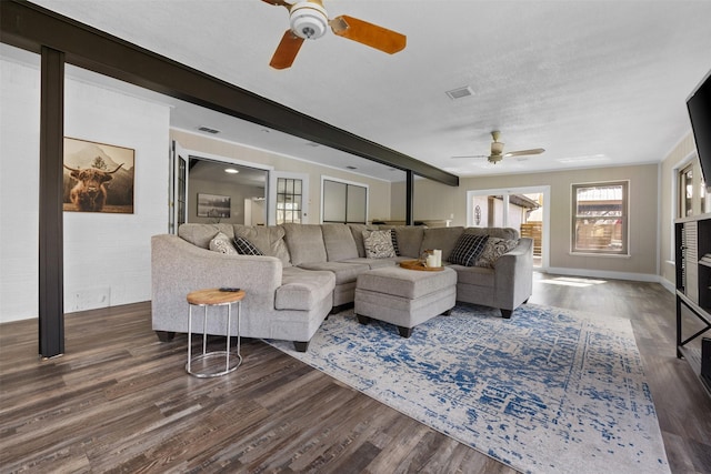 living area featuring baseboards, beam ceiling, visible vents, and wood finished floors