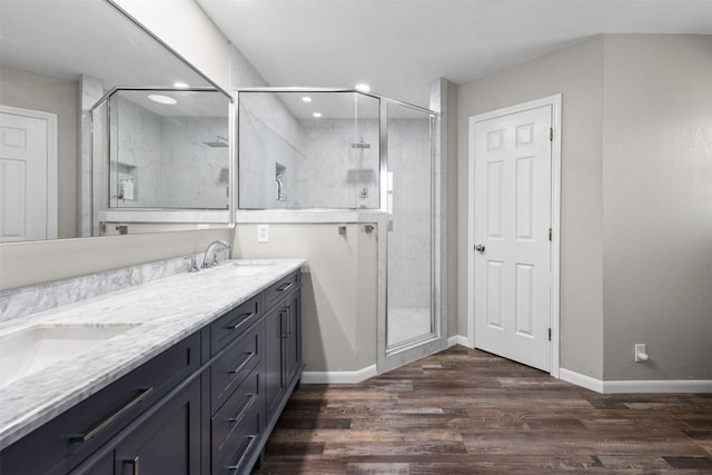 bathroom with double vanity, baseboards, a sink, and wood finished floors