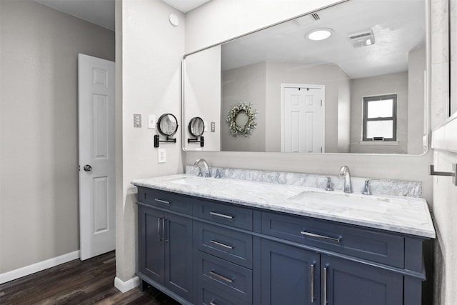 bathroom with double vanity, a sink, baseboards, and wood finished floors