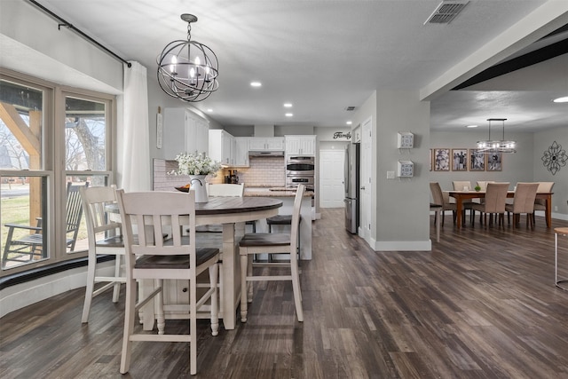 dining area featuring a chandelier, dark wood-type flooring, visible vents, and baseboards