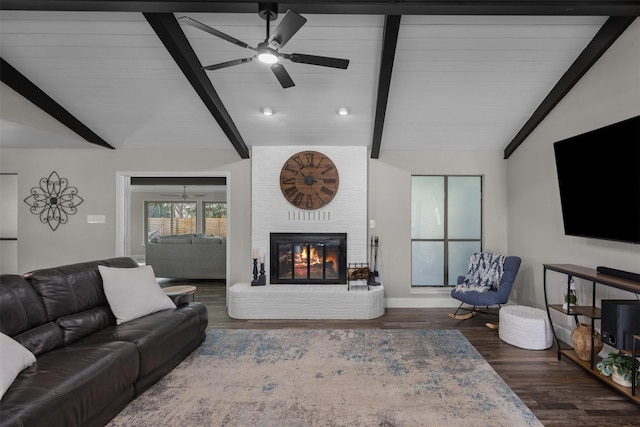 living room featuring ceiling fan, a brick fireplace, vaulted ceiling with beams, and wood finished floors