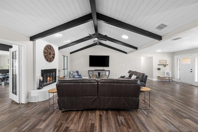 living area with vaulted ceiling with beams, a fireplace, visible vents, and wood finished floors