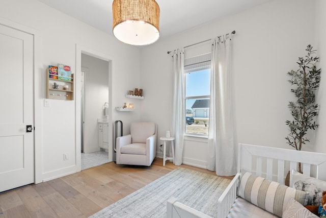 bedroom with light wood-type flooring, baseboards, and ensuite bathroom