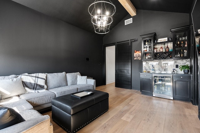 living room with light wood finished floors, a barn door, visible vents, wine cooler, and a chandelier