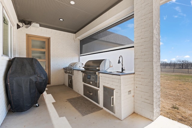 view of patio featuring exterior kitchen, grilling area, and fence