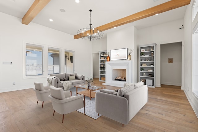 living area with light wood finished floors, a fireplace with raised hearth, beam ceiling, and recessed lighting