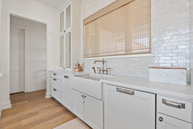 bar featuring a sink, light wood-style flooring, and decorative backsplash