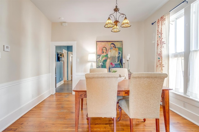 dining room with light wood-type flooring, an inviting chandelier, and baseboards