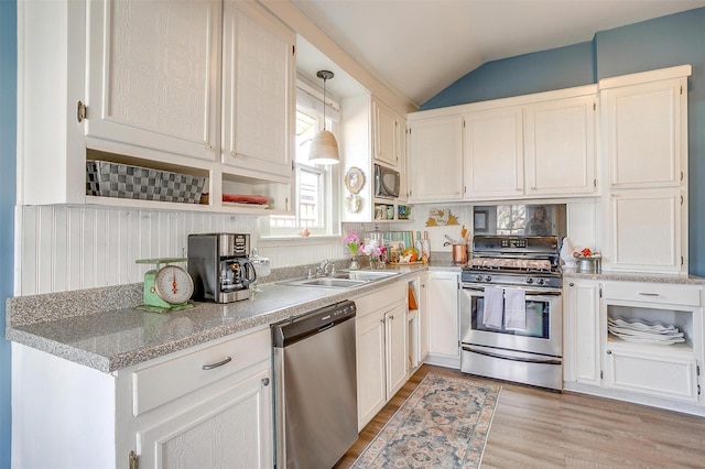 kitchen with light wood-style flooring, appliances with stainless steel finishes, white cabinetry, vaulted ceiling, and a sink