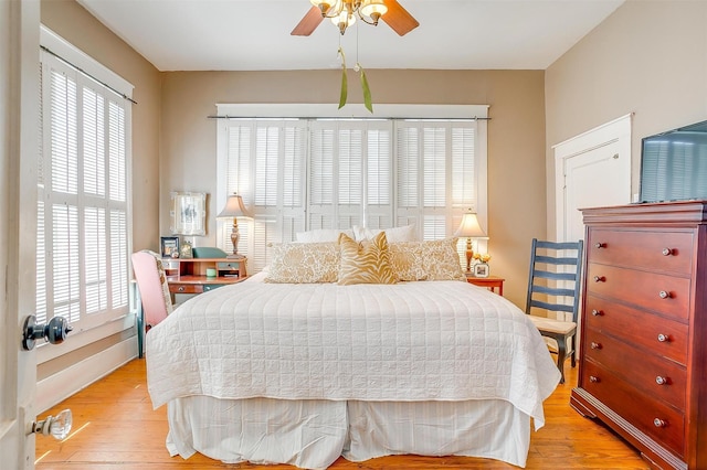 bedroom featuring ceiling fan, light wood finished floors, and multiple windows