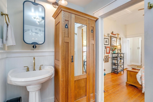 bathroom with a sink, a wainscoted wall, and wood finished floors