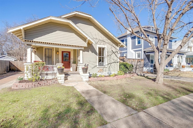 view of front of property with a front yard, covered porch, and fence