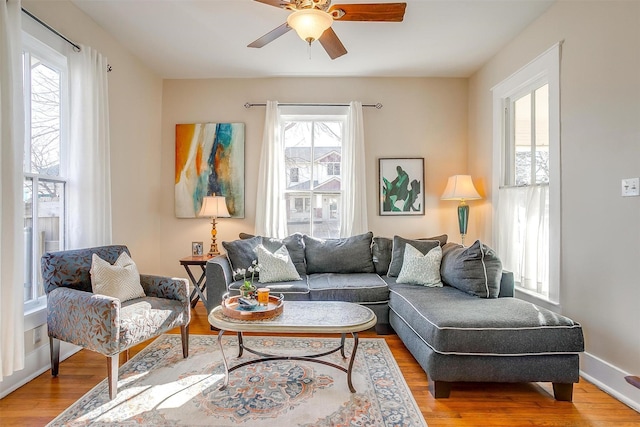 living area featuring a ceiling fan, baseboards, and wood finished floors