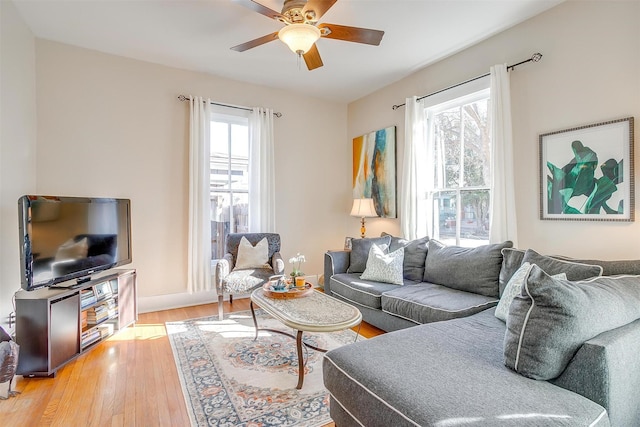 living area featuring light wood-style floors, baseboards, and a ceiling fan