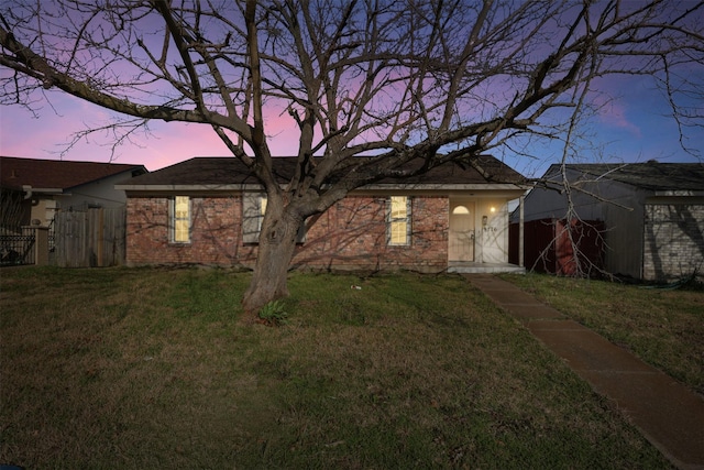 rear view of property with brick siding, fence, and a yard