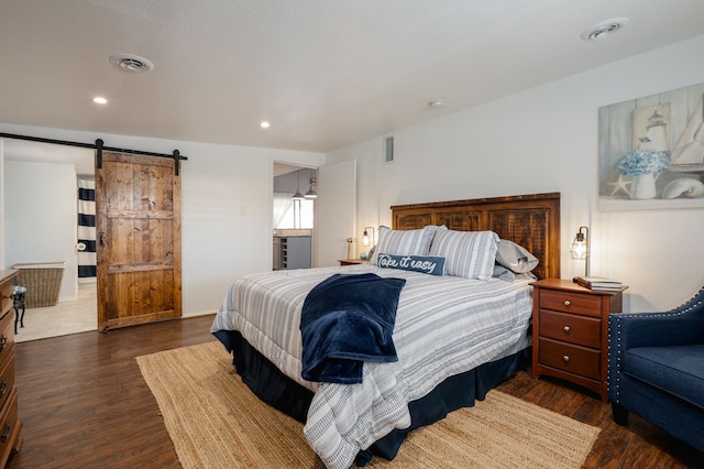 bedroom with recessed lighting, wood finished floors, visible vents, and a barn door