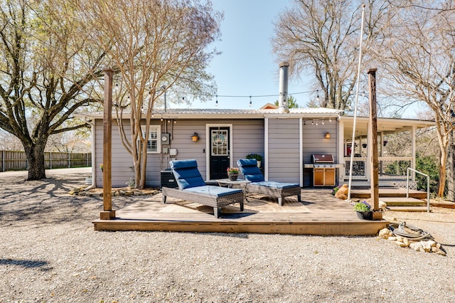 rear view of house featuring metal roof, fence, and a wooden deck