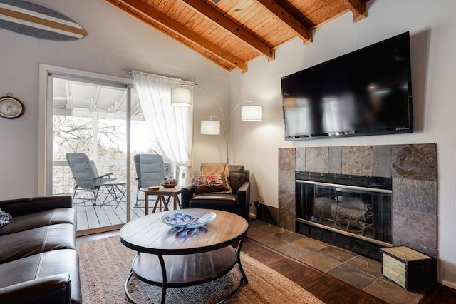 living room featuring lofted ceiling with beams, wood ceiling, and a tiled fireplace