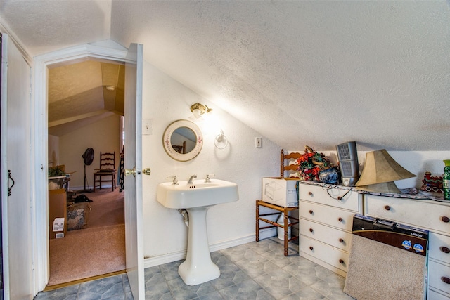 bathroom featuring a textured ceiling, vaulted ceiling, and baseboards