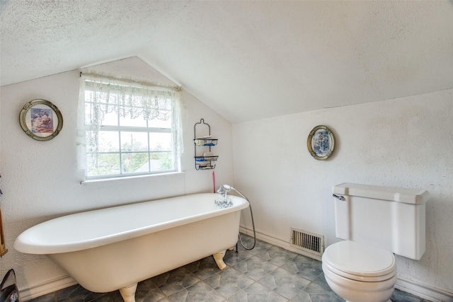 full bath with visible vents, toilet, a soaking tub, lofted ceiling, and a textured ceiling