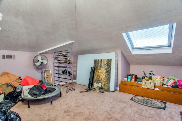 additional living space featuring carpet, visible vents, vaulted ceiling with skylight, and a textured ceiling