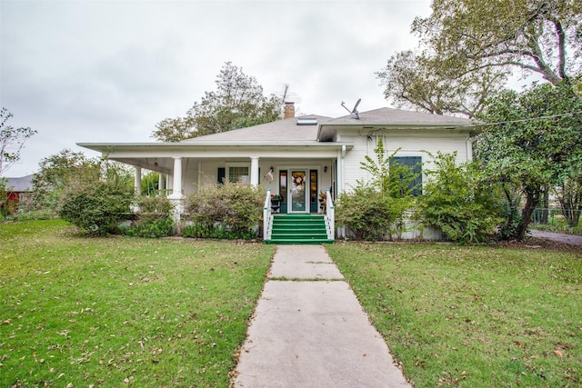 bungalow-style home with covered porch, a front lawn, and a chimney