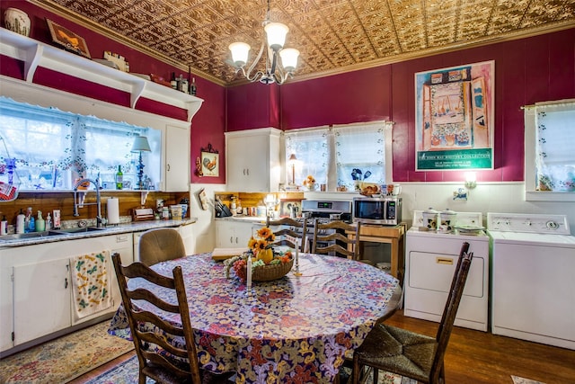 dining room featuring an ornate ceiling, ornamental molding, wood finished floors, an inviting chandelier, and washing machine and dryer