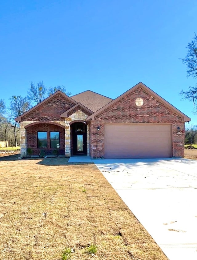 view of front of home with an attached garage, a front lawn, concrete driveway, and brick siding