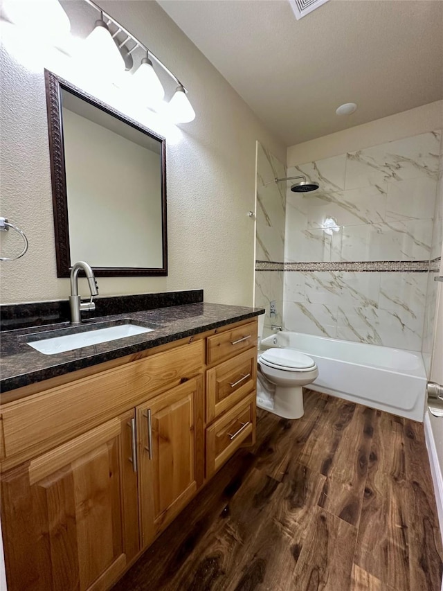 full bath featuring a textured wall, toilet, wood finished floors, vanity, and bathing tub / shower combination