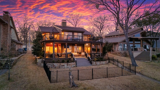 view of front of home featuring stairway, a chimney, fence private yard, and a balcony