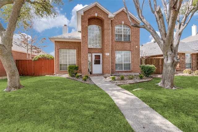 traditional home featuring a front yard, brick siding, fence, and a chimney