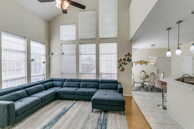 living area with high vaulted ceiling, light wood-type flooring, and ceiling fan