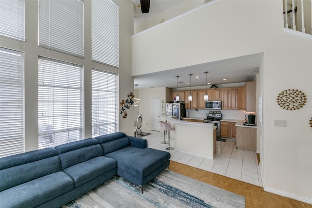 living room featuring light tile patterned floors, recessed lighting, a towering ceiling, and baseboards